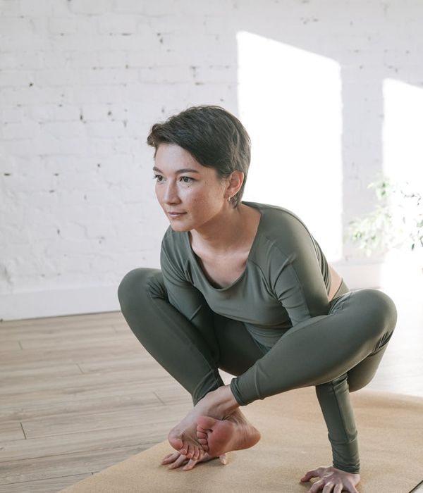 Woman in a calm yoga pose in a dark room with bright light.